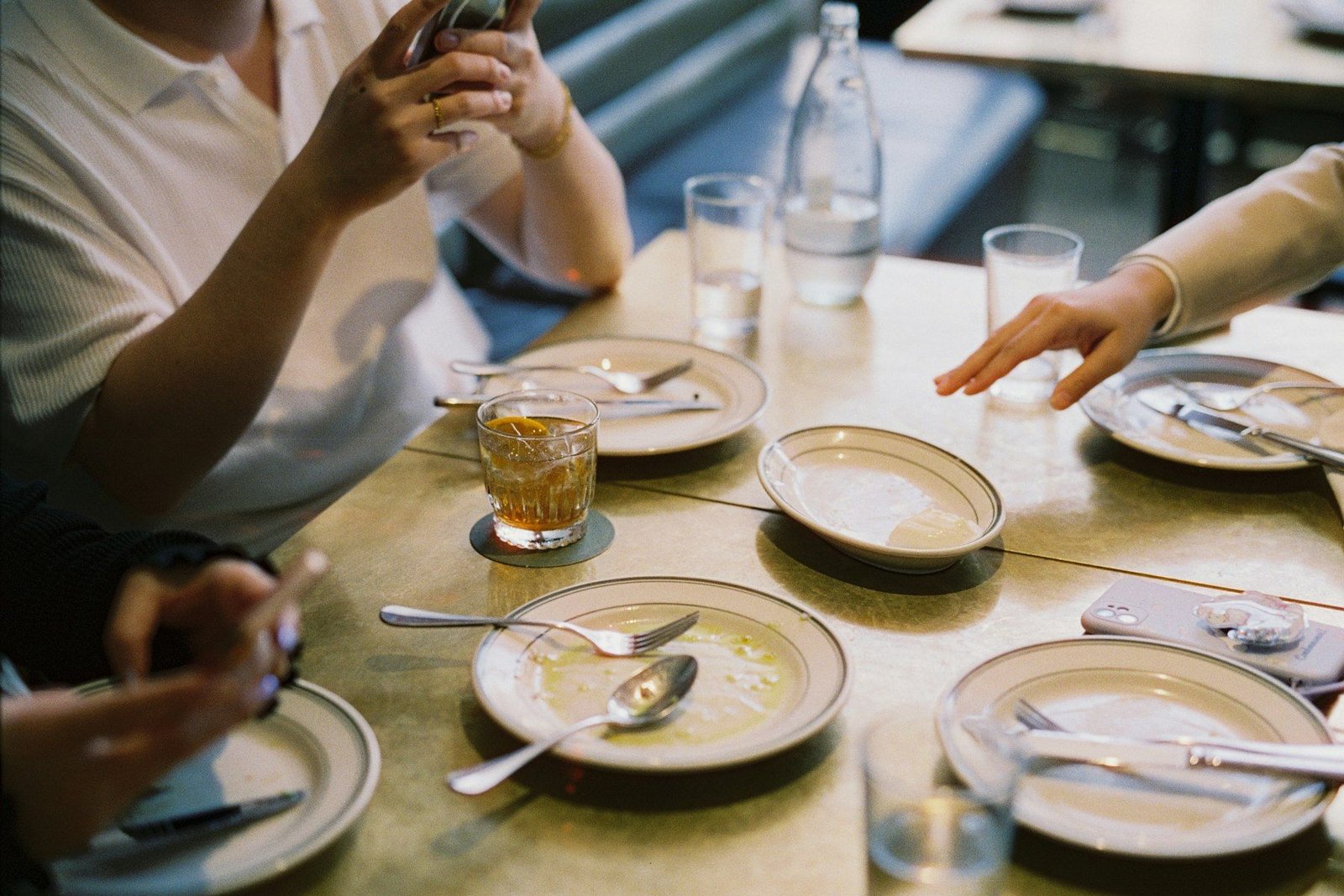 Tavola a fine pranzo con piatti, bicchieri e persone che conversano